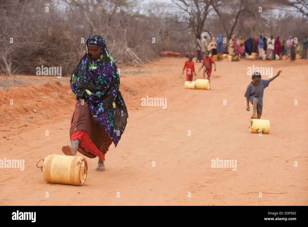 NYTALIYO, NORTH OF ELWAK, EASTERN KENYA, 3rd SEPTEMBER 2009: Women and children roll their round water containers home Stock Photo