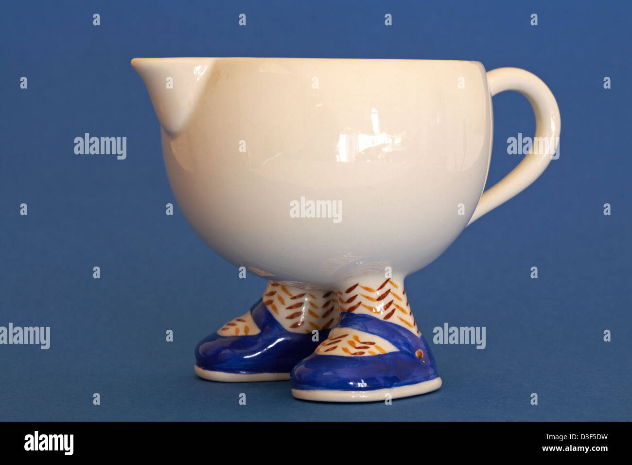 novelty cream coloured jug with feet and shoes isolated on blue background  Stock Photo - Alamy