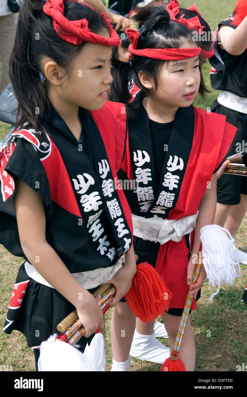 Two little girls wearing red headbands and happi coats partake in festivities at Sagami no Otako Matsuri Giant Kite Festival Stock Photo