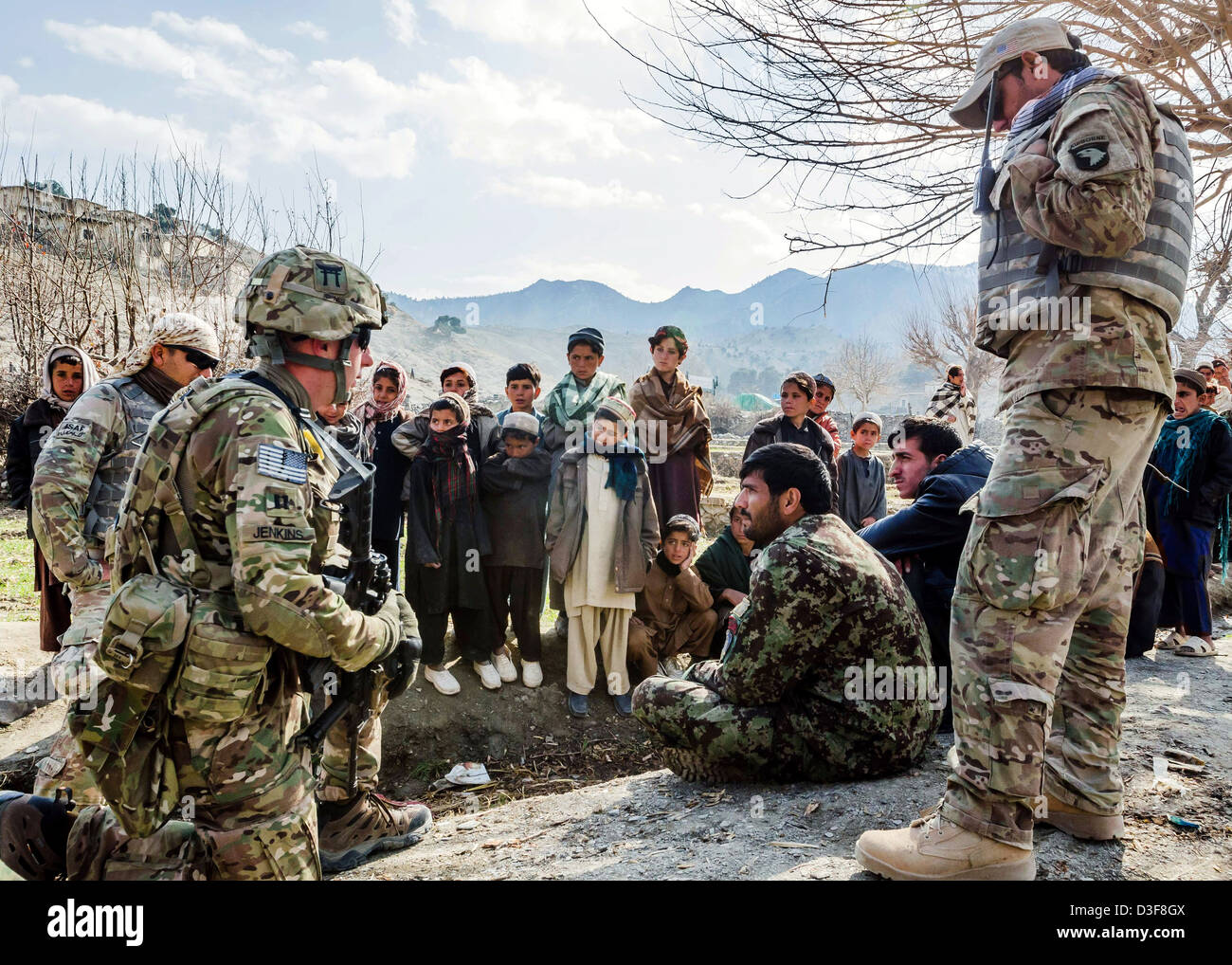 Afghan children gather to watch as US soldiers meet with Afghan National Army soldiers in a remote village January 13, 2013 in Khowst Province, Afghanistan. Stock Photo