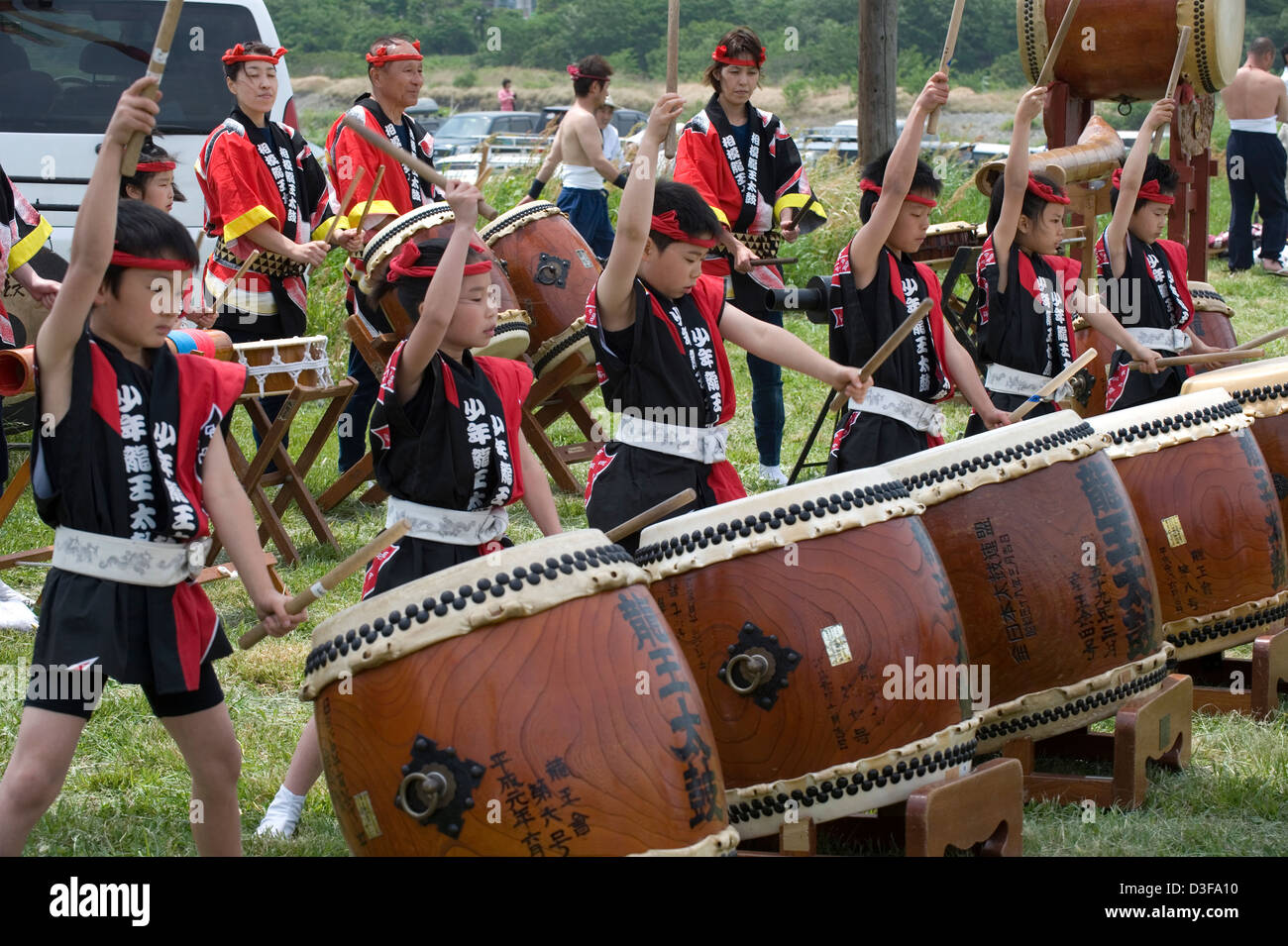 Young boy and girl drummers in festive attire keep beat on Japanese drums providing entertainment at local festival in Japan. Stock Photo