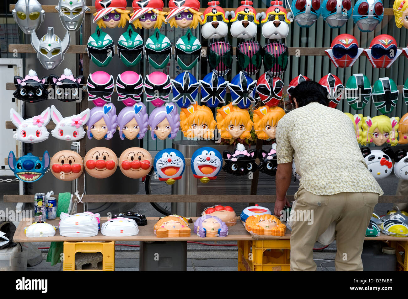 Festival vendor selling plastic anime face masks of popular characters including Anpanman, Doraemon, Ultraman and Power Rangers. Stock Photo