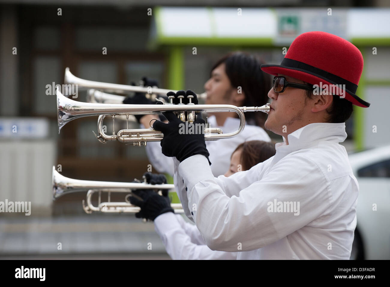 Trumpet players, including guy with red bowler hat and sunglasses, performing in Western-style marching band at festival, Japan. Stock Photo