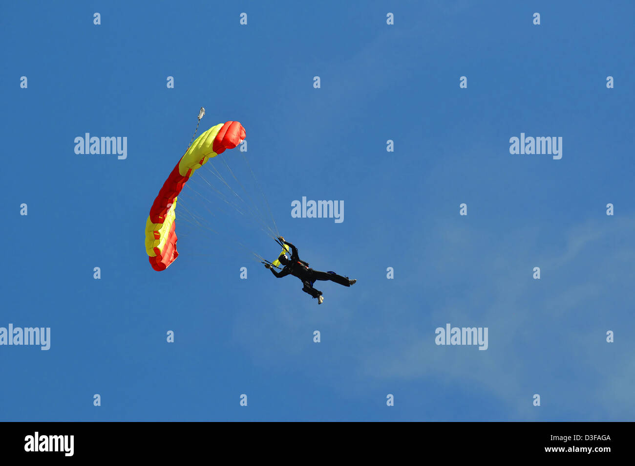 Acrobatic skydiving with colored parachute on blue sky. Stock Photo