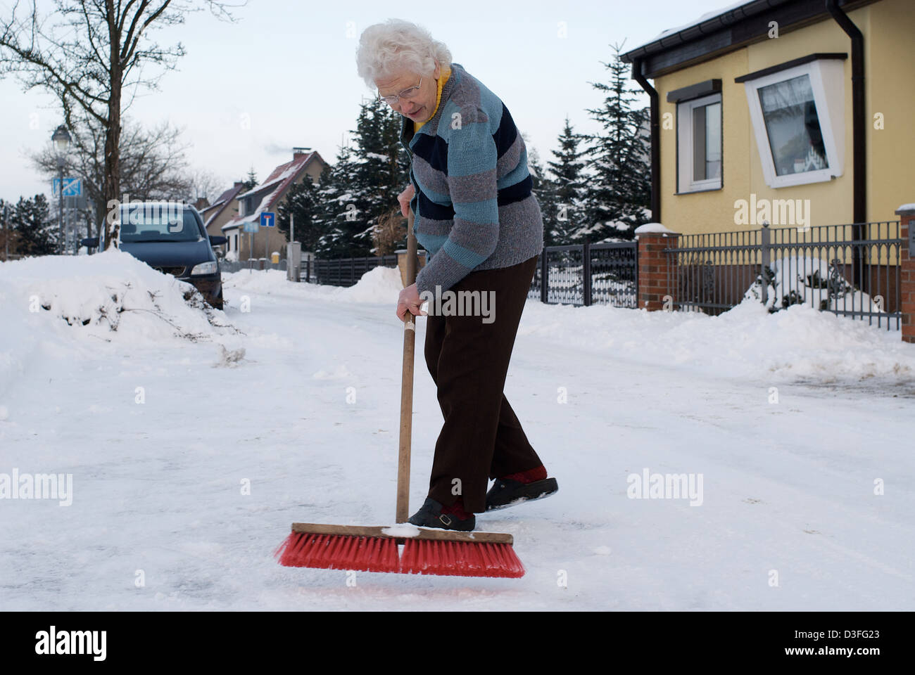 Nauen, Germany, an old woman makes winter maintenance Stock Photo