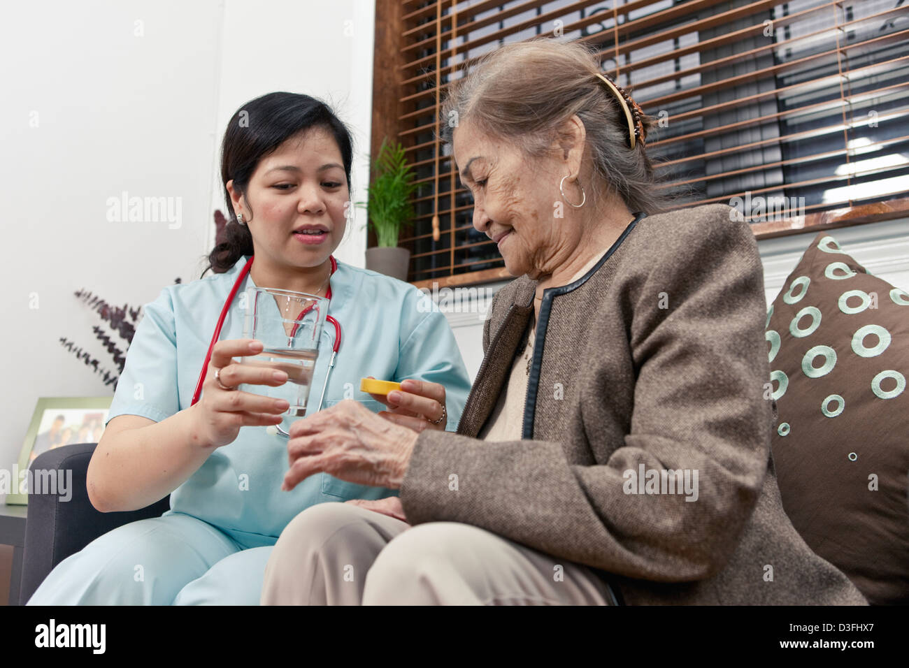 Home care provider keeps senior citizen patient company, helping her take prescription medication Stock Photo