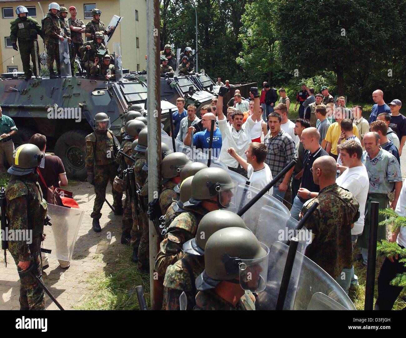 (dpa) - Soldiers of the German army stand in line and shield off a protesting crowd in the army training village at the training area in Wildflecken, Germany, 10 July 2003. The soldiers prepare for their deployment in Afghanistan and exercise different simulated scenarios which are as close to real situations as possible. German Defence Minister Peter Struck wants to extend the dep Stock Photo