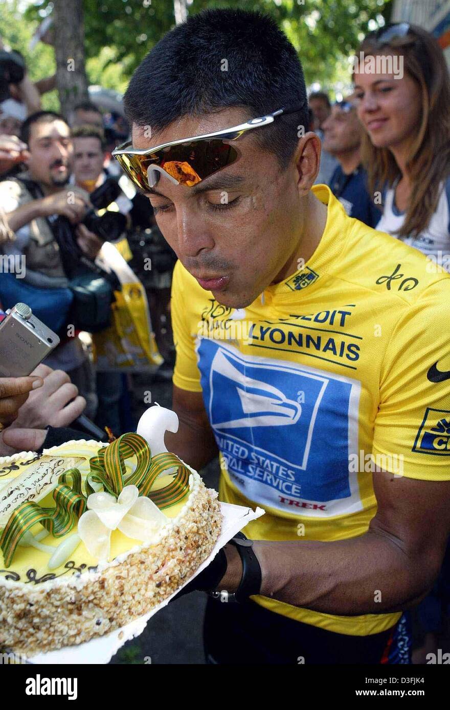(dpa) - Colombian cyclist Victor Hugo Pena (R) (Team US Postal Service) wears the yellow tricot of the front-runner while he blows out the candles on his birthday cake before the start of the fifth leg of the Tour de France in Troyes, France, 10 July 2003. Pena celebrates his 29th birthday today. The fifth leg covers a distance of 196,5 kilometres from the French town of Troyes to  Stock Photo