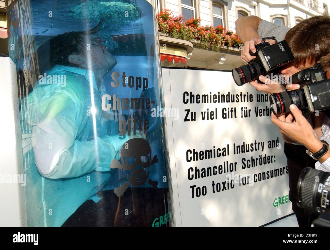 (dpa) - A Greenpeace activist sits in a tank filled with bluish water to protest against the lack of protection against chemical poisons outside the venue of the annual meeting of the European Chemical Industry Council (CEFIC) in Hamburg, 27 June 2003. The writing on the tank reads 'Stopp Chemiegifte' (stop chemical poisons). Stock Photo