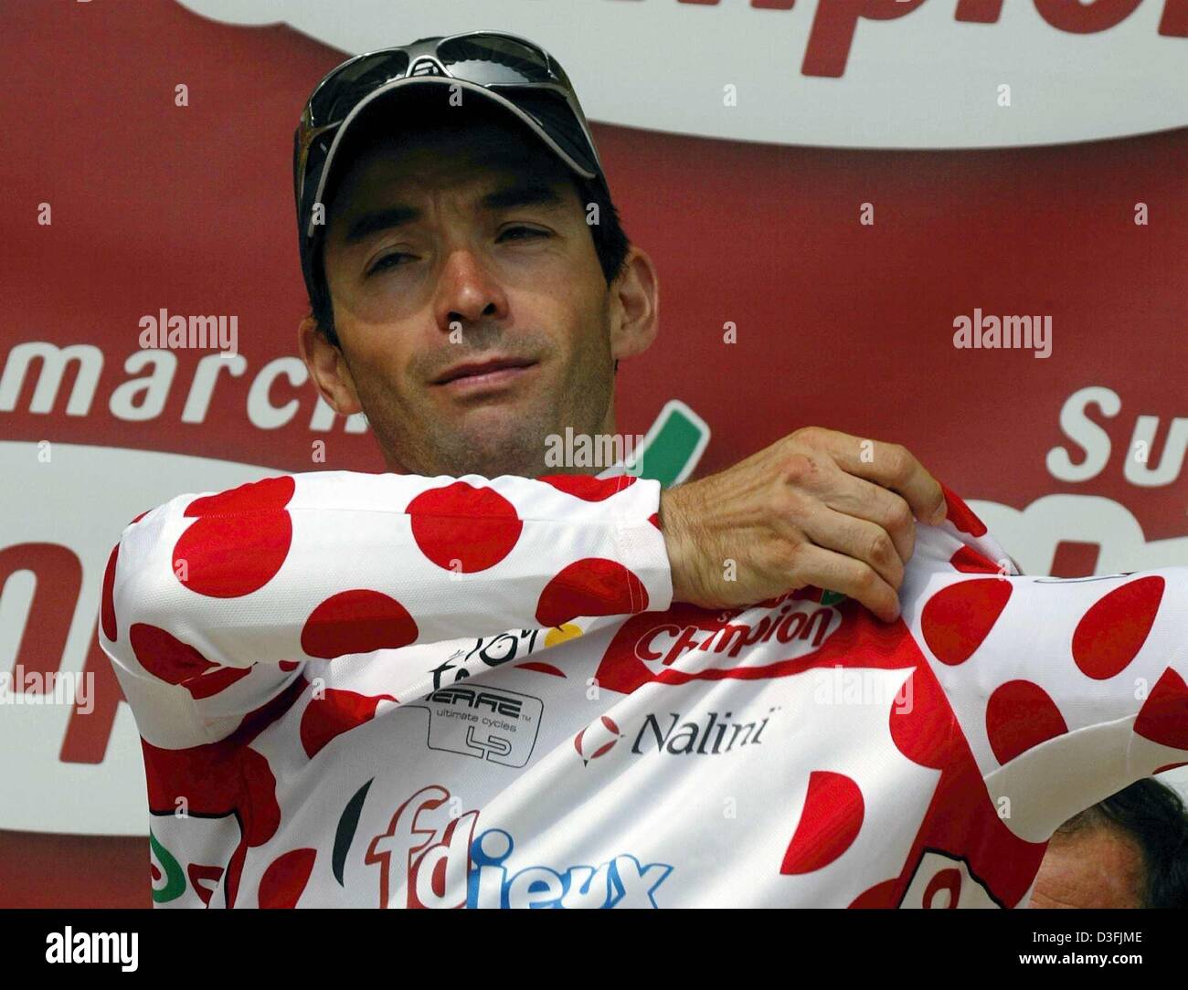 (dpa) - French cyclist Christophe Mengin of the team FDJeux puts on the red and white polka-dotted jersey of the best climber after the third stage of the Tour de France cycling race, in Saint Dizier, France, 8 July 2003. The third stage led from Charleville-Mezieres to Saint Dizier over a distance of 167.5 km. Stock Photo