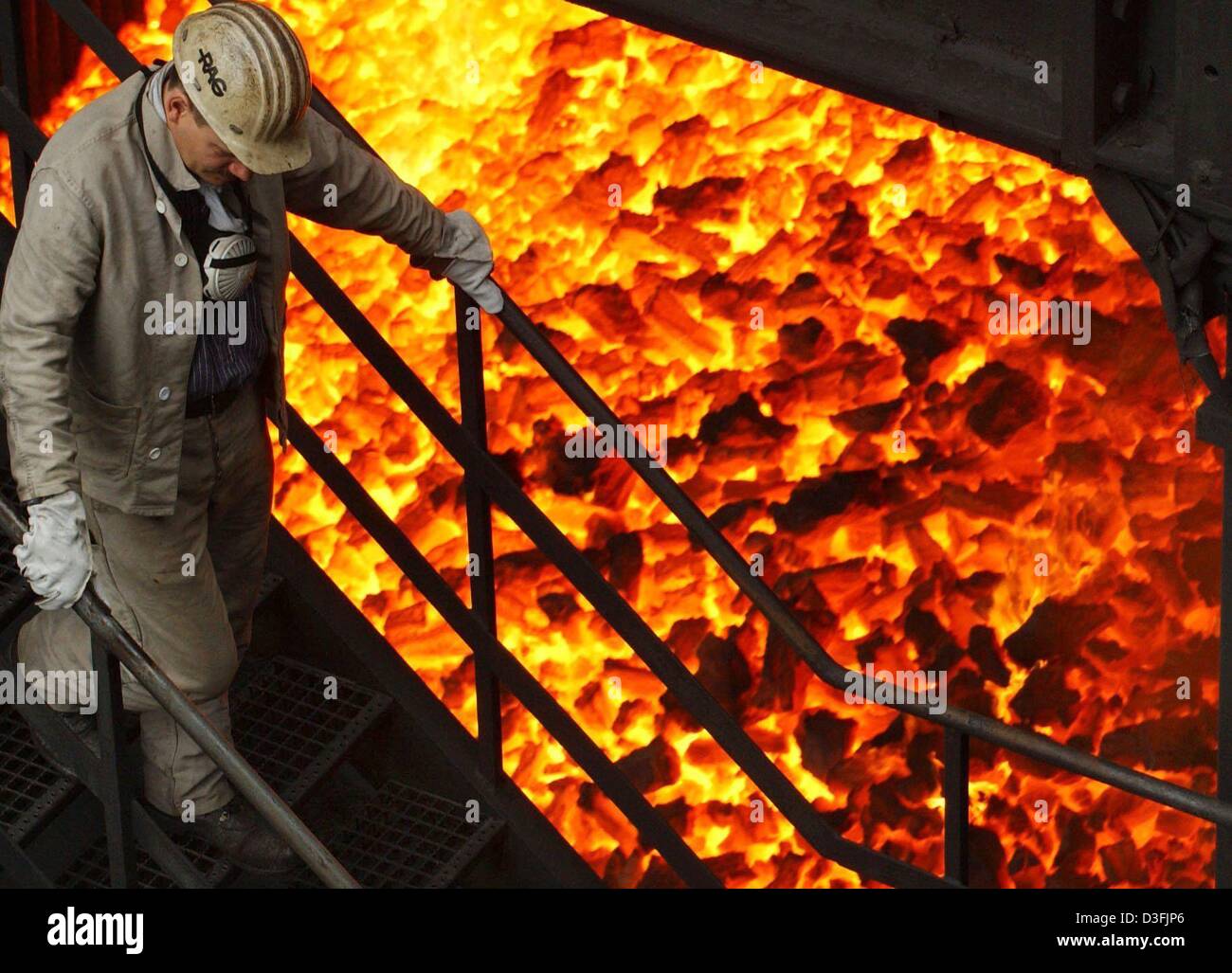 (dpa) A worker passes a waggon filled with red hot coke in the coking