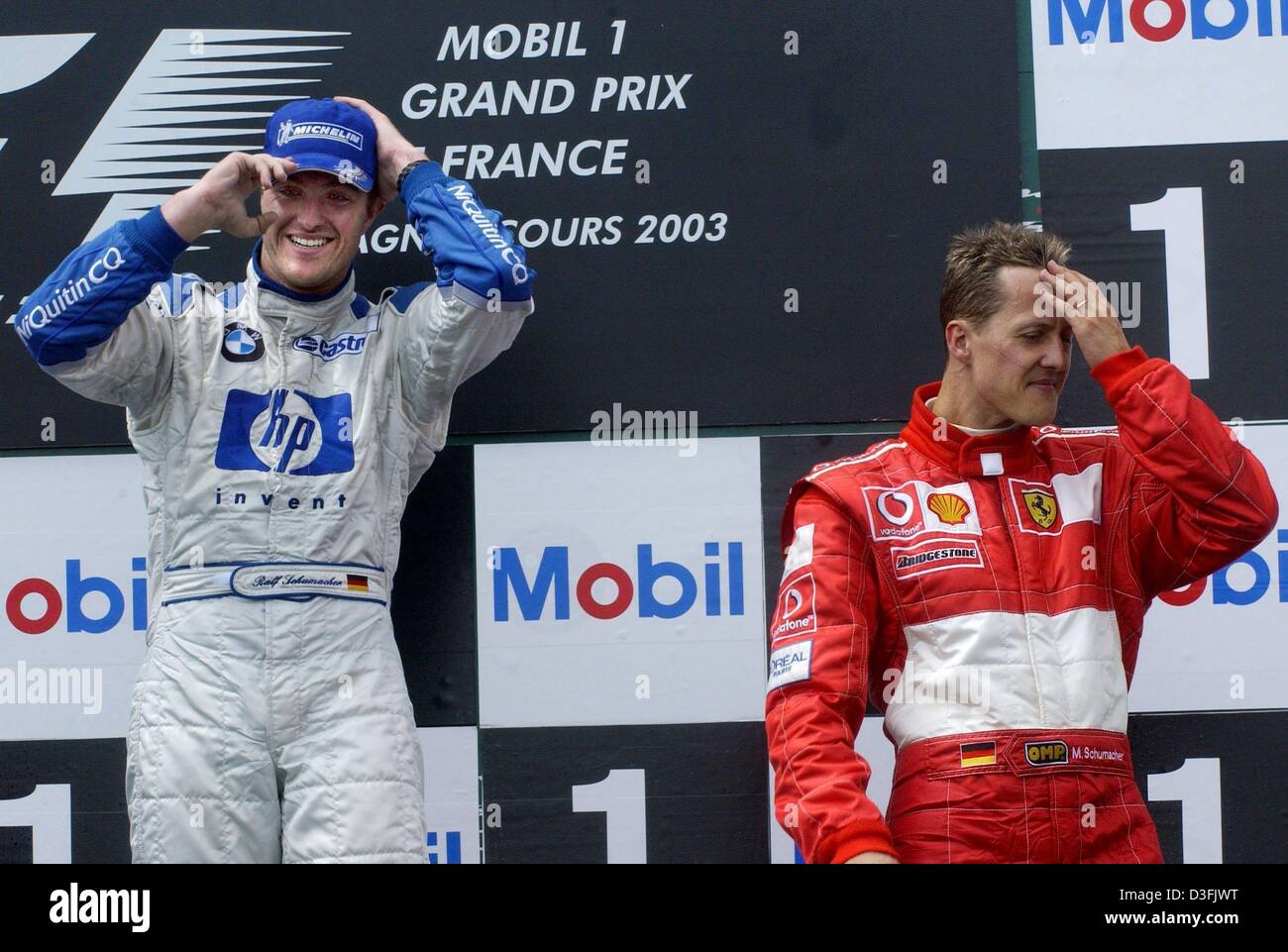 (dpa) - German formula one pilot Ralf Schumacher (L, BMW Williams) smiles after a shower of champagne while his brother, formula one driver Michael Schumacher (Ferrari), looks thoughtful after the French formula one Grand Prix in Magny-Cours, France, 6 July 2003. Ralf Schumacher finished first, his brother third. Stock Photo