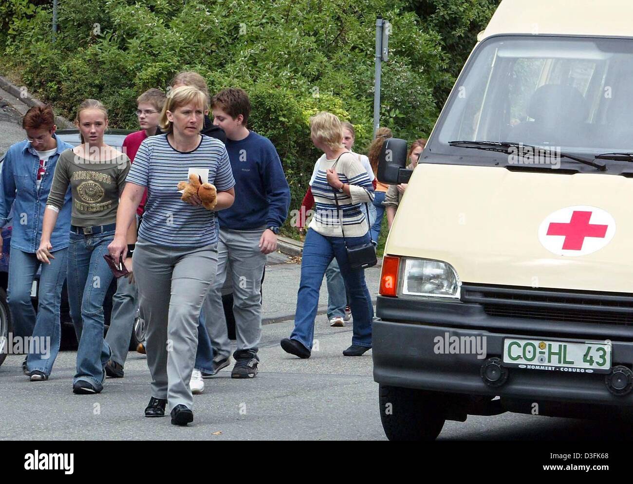 (dpa) - Students, teachers and parents walk along a street past an ambulance at a school in Coburg, Germany, 2 July 2003. According to the police a 16-year-old student was handling a gun in the classroom at school when a shot was triggered. The bullet went into the ceiling but when the teacher attempted to take the gun off the student she was shot in the thigh. The other students r Stock Photo