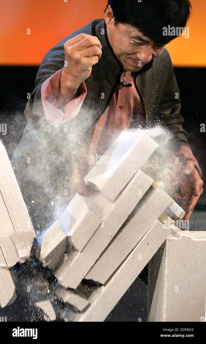 (dpa) - Actor Jackie Chan smashes a block of four stone plates while holding an egg in his fist during the German television show 'Wetten, dass...?' (bet if...?) in Nuremberg, Germany, 11 December 2004. (POOL) Stock Photo