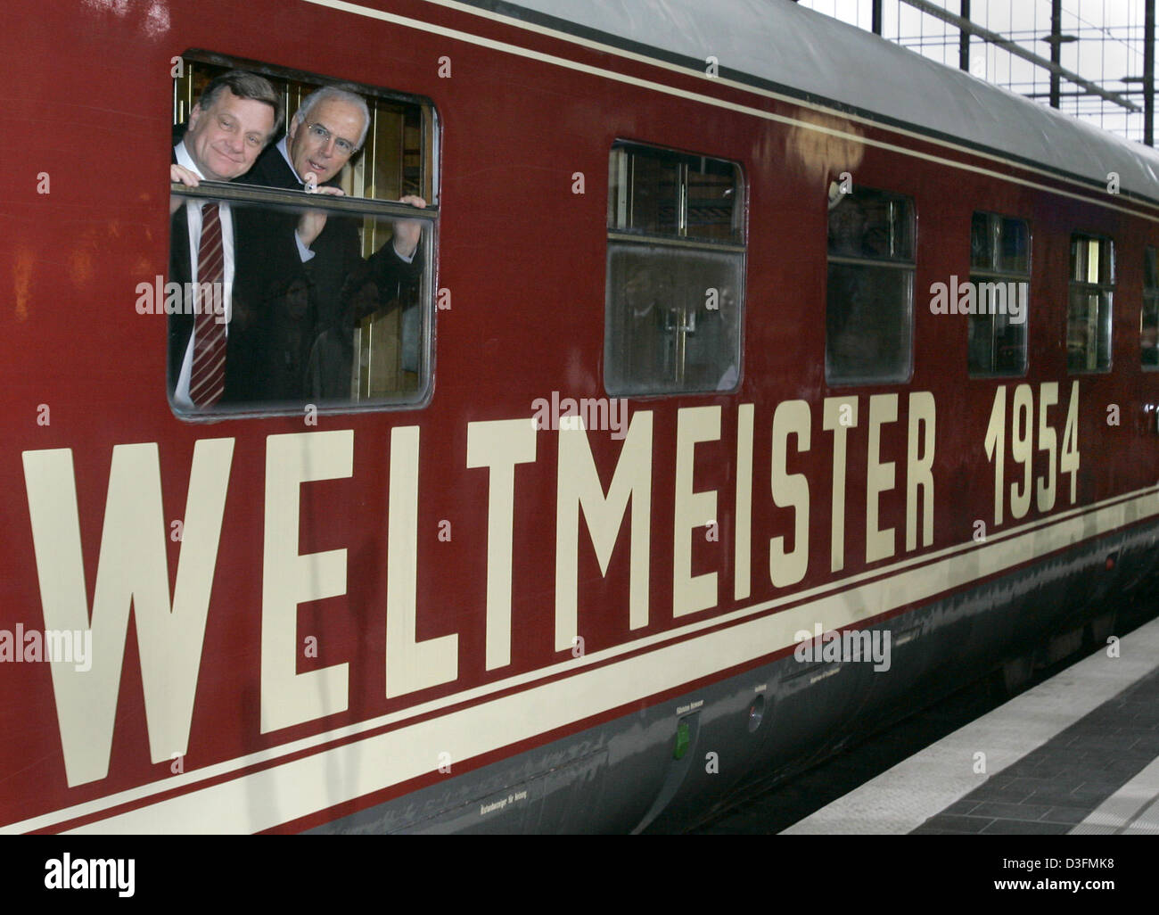 (dpa) - Hartmut Mehdorn (L), chairman of the Deutsche Bahn (DB, German railway), and Franz Beckenbauer, head of the 2006 FIFA World Cup Organizing Committee, look out of a window of the original train with which the first German World Cup winners in 1954 toured the country in Berlin, Germany, 7 December 2004. The Deutsche Bahn has been selected as the final national sponsor for the Stock Photo