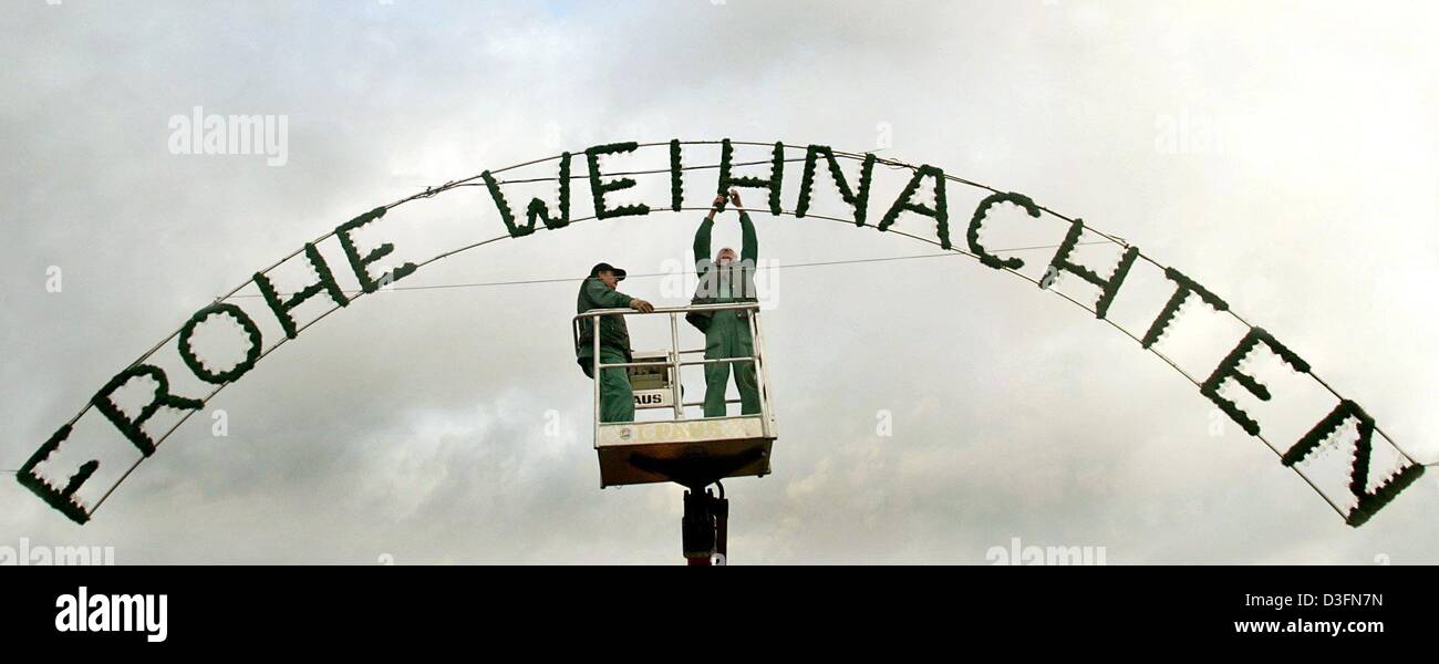 (dpa) - Two workers fit the writing 'Frohe Weihnachten' (Merry Christmas) in the shape of a light installation on the market place in Haldensleben, Germany, 22 November 2004. Stock Photo
