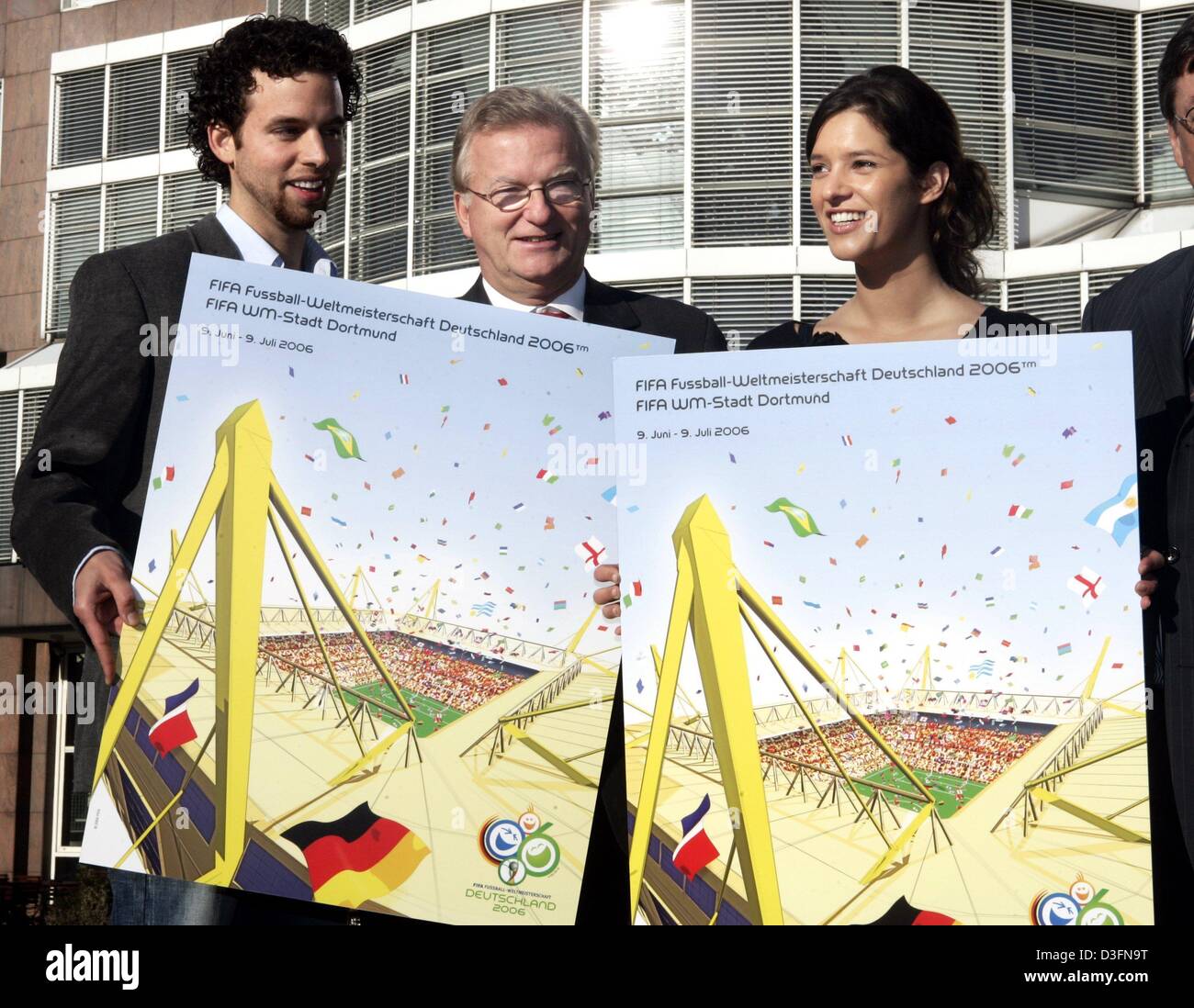 (dpa) - Along with Borussia Dormund official Gerd Niebaum present College students Oliver Koetting (l) and Kathrin Winkler (R) their design which has been chosen as the official FIFA Soccer World Cup 2006 poster for the city of Dortmund, Germany, 24 November 2004. The poster was chosen out of 70 poster entries and shows Dortmund's Westfalenstadion which will host six games during t Stock Photo