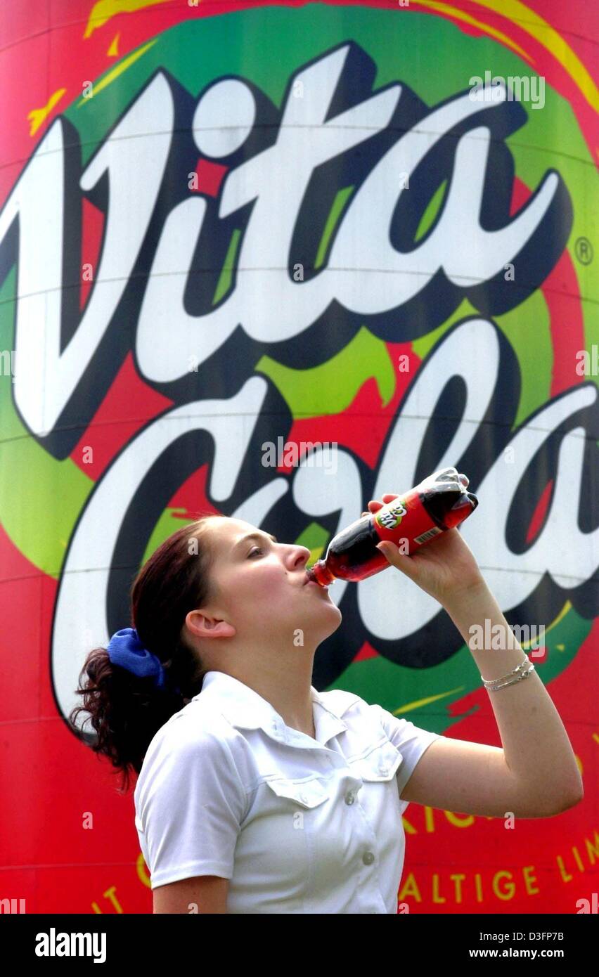 (dpa files) - Daniela Ilgen drinks a bottle of Vita Cola in front of the brand logo at the production site of the soft drinks and water company Thuringia Waldquell Mineralbrunnen GmbH in Schmalkalden, eastern Germany, 24 June 2002. Lacking the import of western products, Vita Cola was invented in the former German Democratic Republic (GDR) in 1954. After the Berlin Wall came down,  Stock Photo