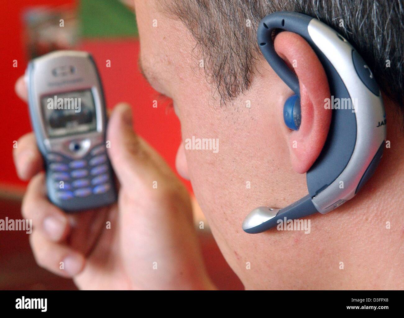 dpa) - A user wears a Bluetooth earplug Jabra BT-200 which be used for hands-free with a mobile phone, in Leipzig, Germany, 6 April 2003. The Bluetooth wireless connection works
