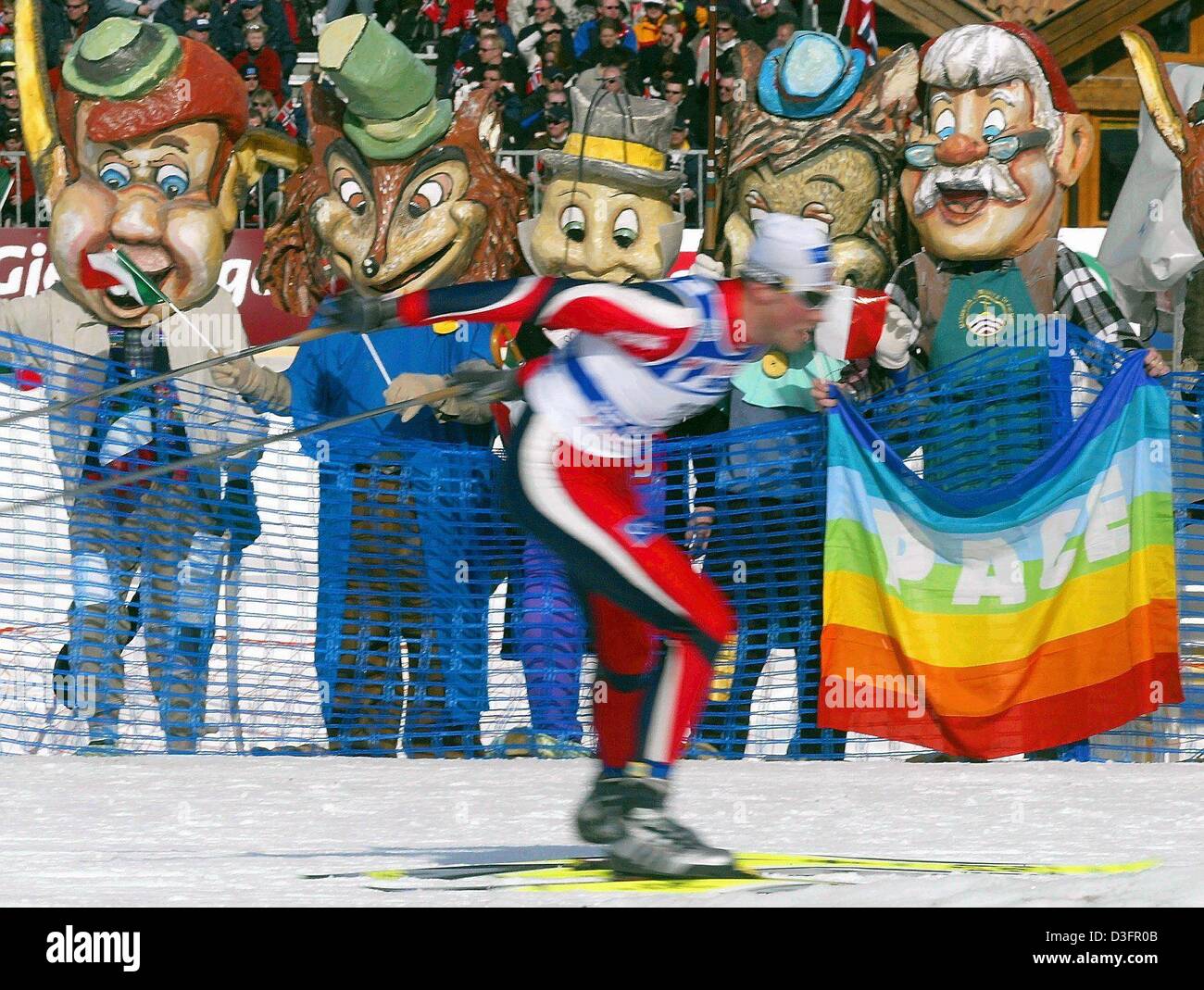 (dpa) - Carnivalists hold up a rainbow-coloured peace flag reading 'Pace' (peace) as they watch the men's 50km sprint of the Nordic Skiing World Championships in Tesero in the Val di Fiemme, Italy, 1 March 2003. Stock Photo