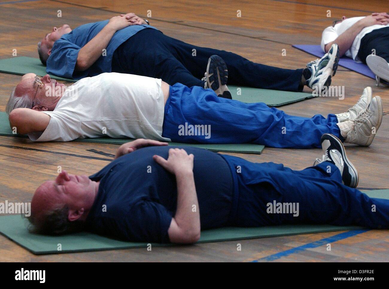 (dpa) - A group of senior citizens lie down on mats on the ground during an exercise programme at a sports club in Berlin, 28 April 2003. Senior women and men, members of the sports club, are keeping fit through sporting exercises. The Berlin regional sports association has around 529,529 members. 122,506 are over the age of 50. 23.1 percent are active in sports groups for seniors. Stock Photo