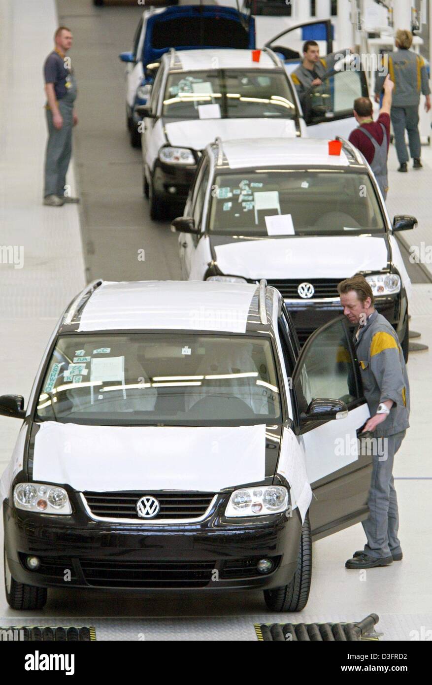 (dpa) - A Volkswagen employee is doing the final check on the new model VW Touran in Wolfsburg, Germany, 26 March 2003. The Touran is a compact van based on the model of the VW Golf and has been offered since March for less than 20,000 euros. Volkswagen plans to sell 130,000 Tourans in 2003 and 180,000 in 2004. The workers are wearing boilersuits with the 'Auto 5000' logo - they we Stock Photo