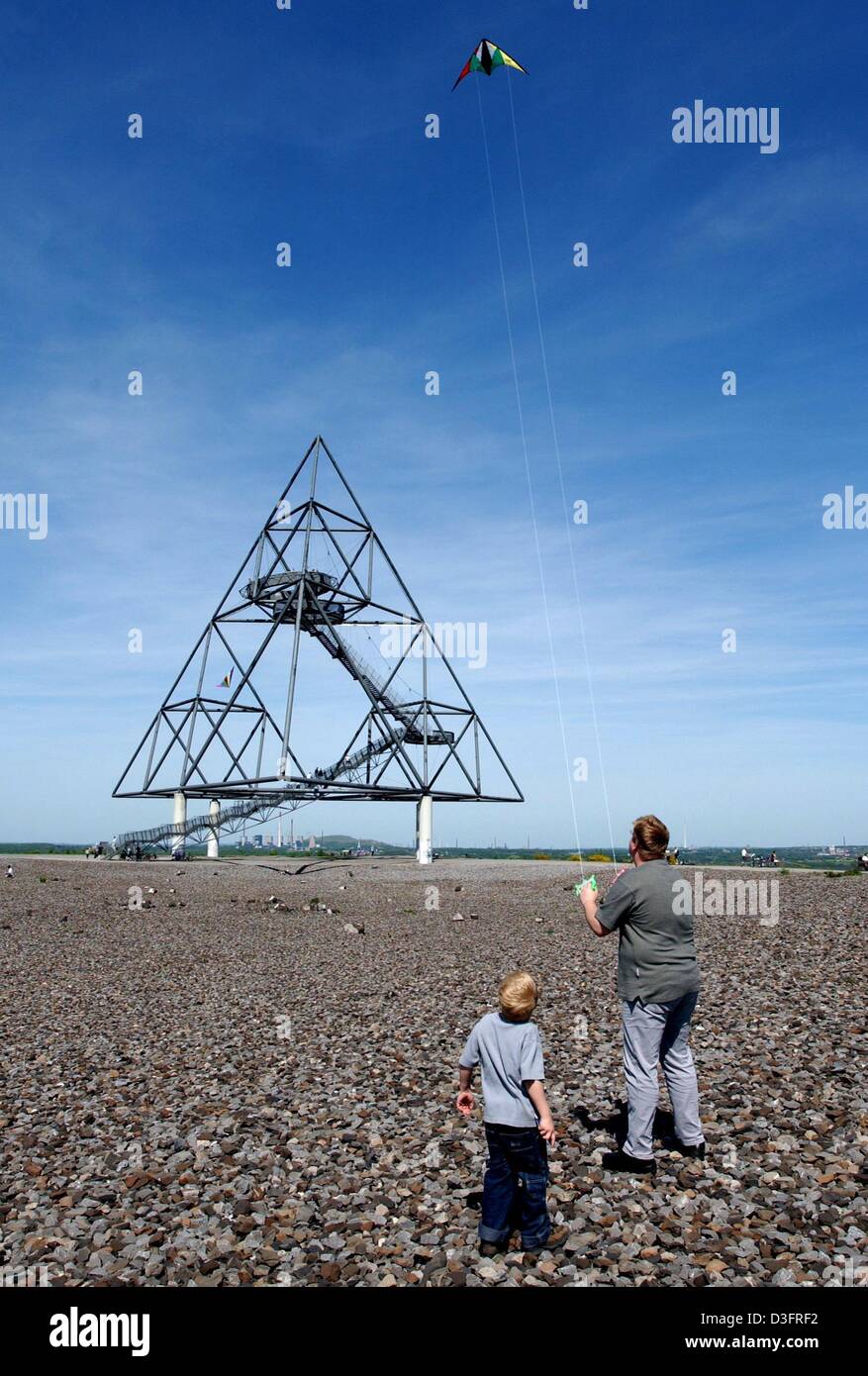 (dpa) - A father and his son fly a kite in front of the Tetraeder on the stone heap in Bottrop, Germany, 3 May 2003. The Tetraeder is a work of art which was built in the context of the international construction exhibition in 1994. It weighs 230 tons and is about 165 metres in height. Locals call the heap also 'Monte Schlacko' and use it as a favourite lookout point. Stock Photo