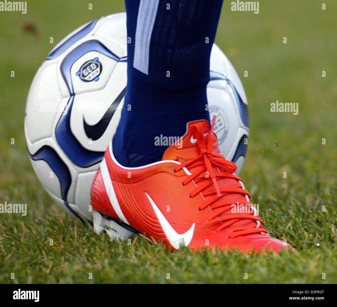 (dpa) - A bright orange Nike soccer shoe partially covers a Nike soccer ball on a soccer field in Berlin, Germany, 8 February 2003.  Marcelinho, a midfielder for Hertha BSC Berlin, recently began wearing the eye-catching shoe, which is new to the Nike line. Stock Photo