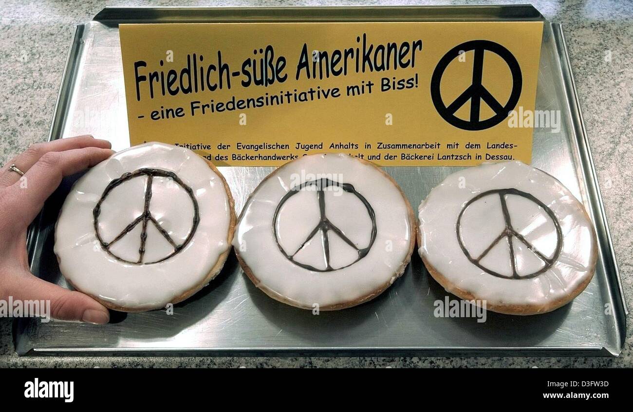 (dpa) - A hand takes a piece of pastry with the traditional sign of peace movements on top, made of chocolate, in a bakery in Dessau, Germany, 21 February 2003. In Germany, black and whites are traditionally called 'Amerikaner' (Americans) and are sold under the motto: 'Friedlich-suesse Amerikaner' (peaceful sweet Americans). This is how bakeries of the German state of Saxony-Anhal Stock Photo