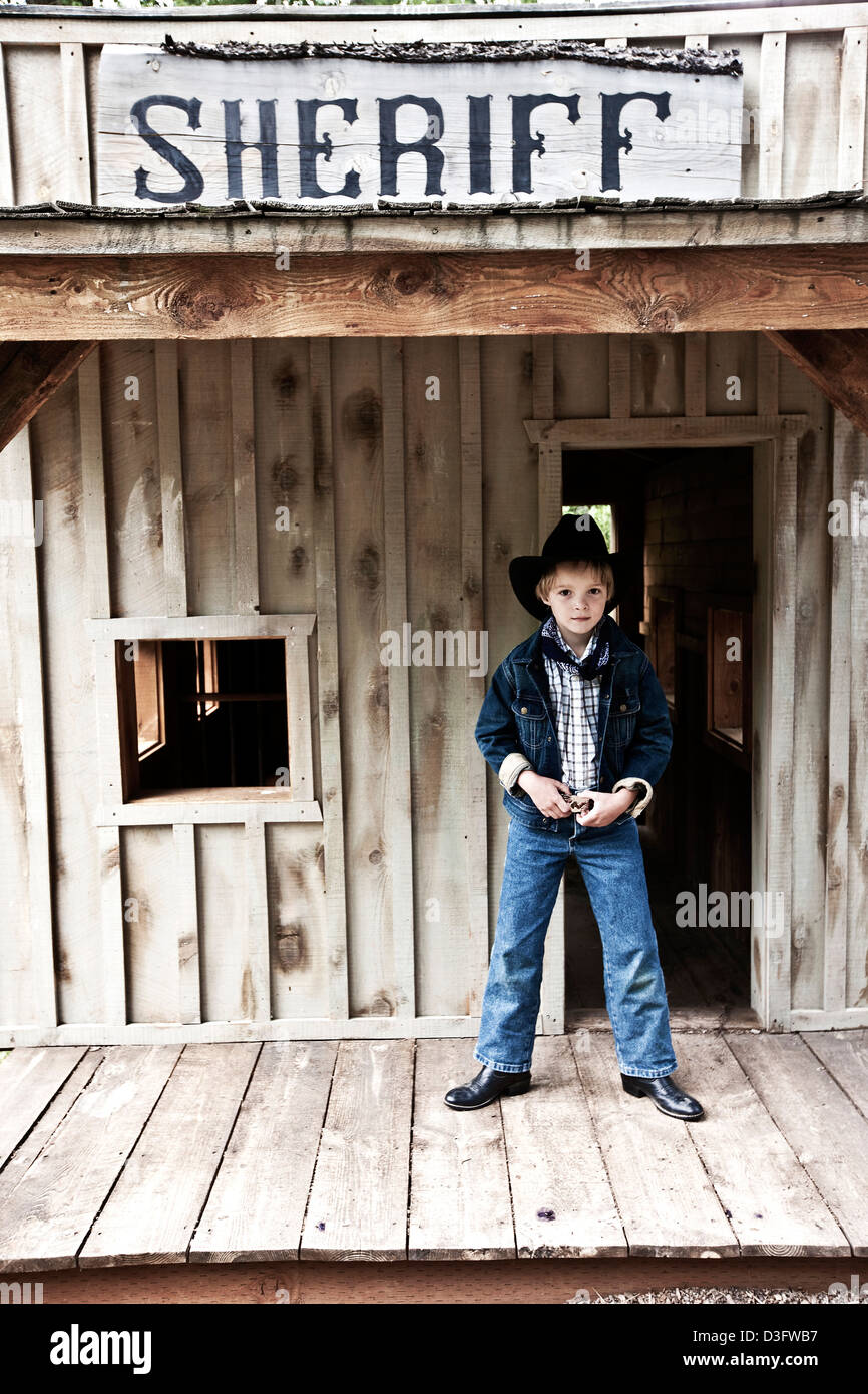 Young boy dressed as Sherif on veranda of Wild West buildings on ranch in Montana, USA Stock Photo