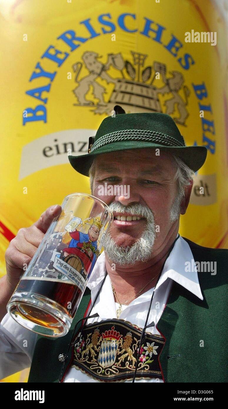 (dpa) - With a glass of beer in his hand, Hans Birzer stands near the beer fountain in Munich, Germany, on the 'Tag des Bayerischen Bieres 2003' (day of the Bavarian beer 2003), 23 April 2003. The day of the beer marks the beginning of the Bavarian beer week. Until 30 April, exhibitions, seminars and games on and with beer are offered by breweries, restaurants and tourism associati Stock Photo