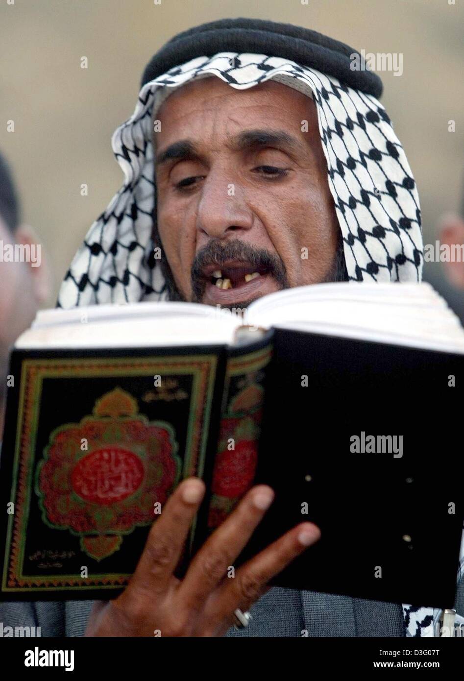 (dpa) - An Iraqi Shiite muslim wearing a kufiyeh is reading prayers from a richly decorated book, Karbala, 22 April 2003. Hundreds of thousands of Shia muslims have gathered in the holy city of Karbala for the climax of a religious pilgrimage that has been banned for a quarter of a century. They commemorate the death in the 7th century of Imam Hussein, grandson of the Prophet Moham Stock Photo