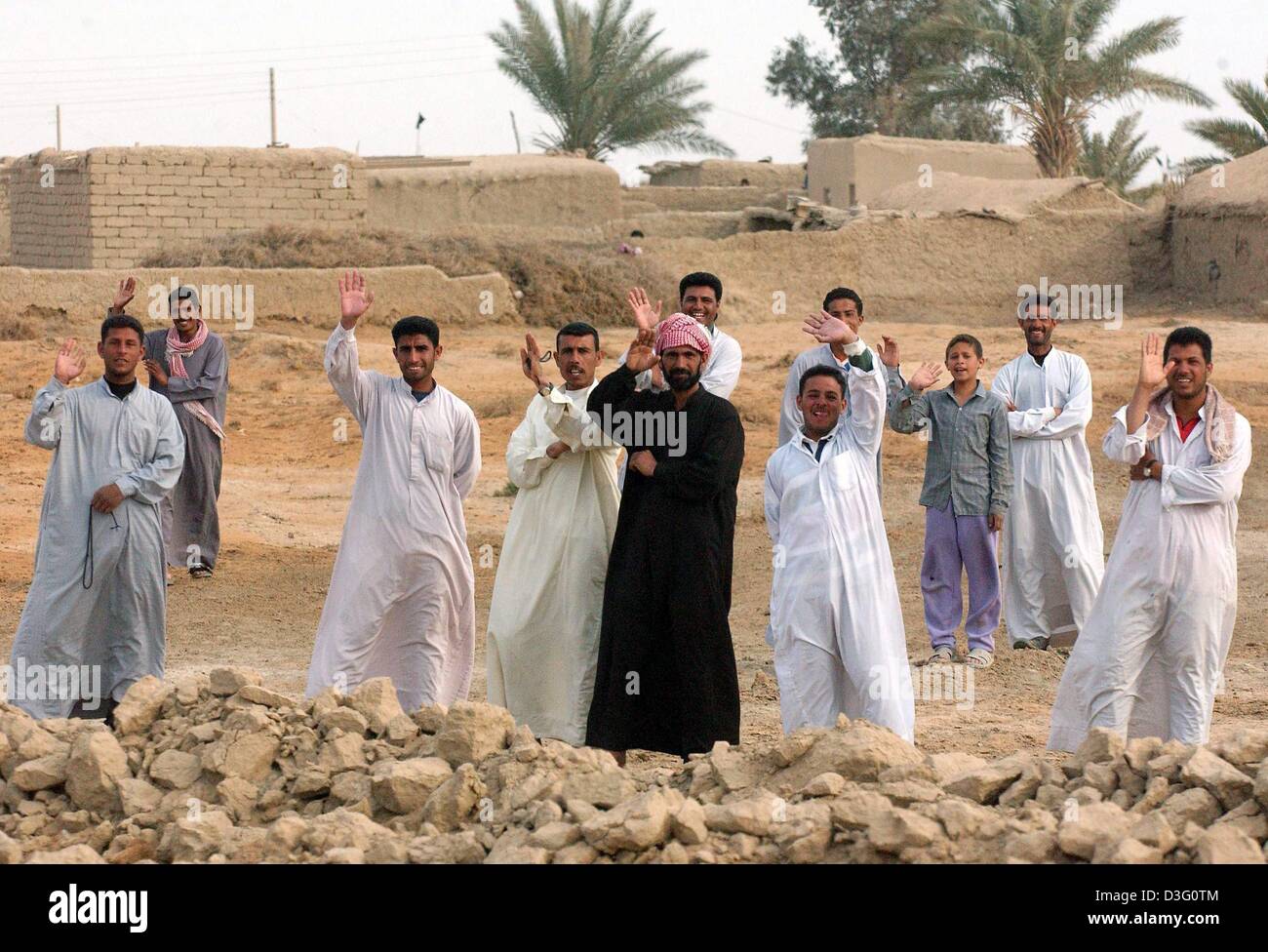 (dpa) - A group of Iraqi civilians wave their hands and greet the approaching US Marines of the 3rd Light Amoured Reconnaissance Battalion (3rd LAR) who are on a reconnaissance mission around 90 kilometres south of Baghdad near An Nu Maniyah, Iraq, 2 April 2003. The US Marines prepare for the decisive advance on Baghdad after days of rest. Stock Photo