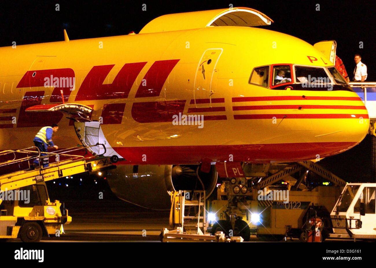 (dpa) - A cargo aircraft is being unloaded at night at the airport in Frankfurt, Germany, 28 March 2003. In the course of the ongoing rebranding of the cargo  company DHL the fleet of aircrafts will be painted yellow. DHL's logistic partner, the Deutsch Post (german mail), will also apply this colour scheme to their fleet of cars and and transport vehicles. So far aircraft and curi Stock Photo