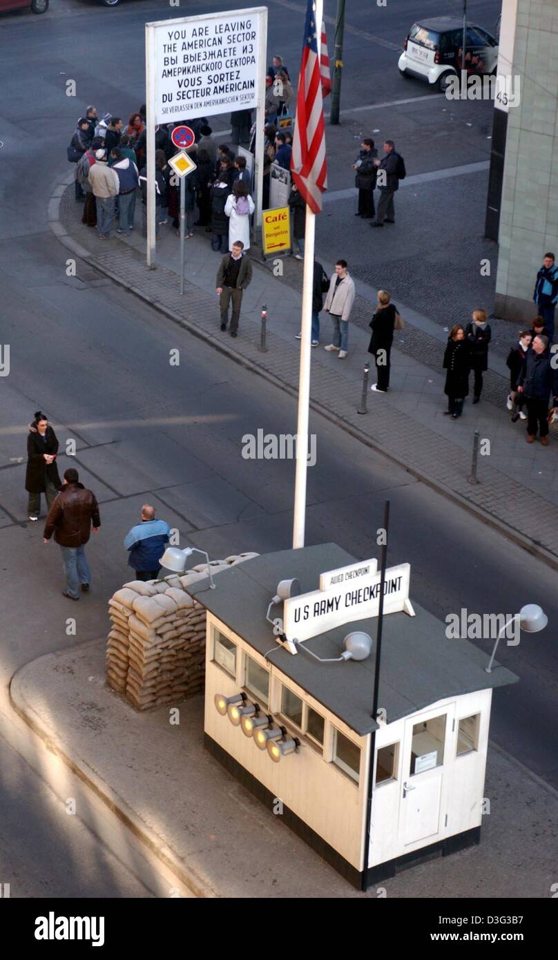 (dpa) - People cross the street in front of the museum 'Checkpoint Charlie' which is a frequently visited tourist sight of Berlin, 25 February 2003. Each year, more than 600,000 people visit the former checkpoint for people who wanted to go to East Berlin. The passage became known two months after the wall had been built on 13 August 1961. US and Soviet tanks faced one another. US  Stock Photo