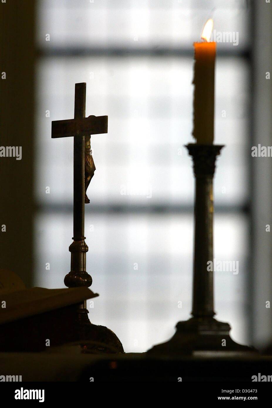 (dpa) - A crucifix stands next to a burning candle on the altar during a service of the top leaders of the Protestant churches in Europe, in the French Cathedral in Berlin, 5 February 2003. Church members from Europe, the United States and the Middle East met to concertedly find an answer to the looming war in Iraq. Stock Photo