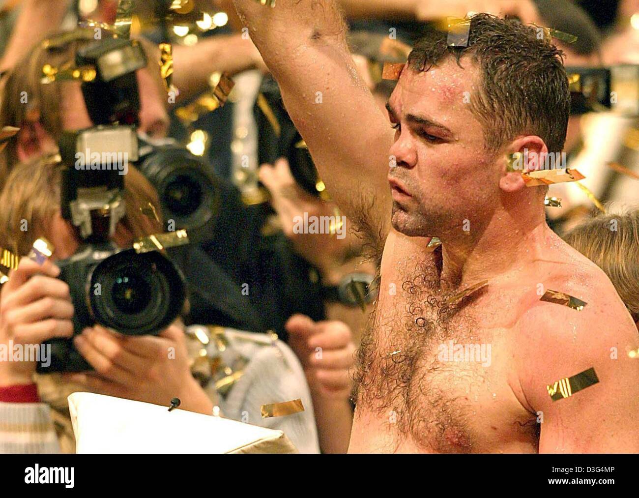 (dpa) -  German Boxing World Champion Sven Ottke (C) stands surrounded by photographers and gestures triumphantly after defeating Britain's Robin Reid (not in frame) during their IBF and WBA super middleweight World Championship fight in Nuremberg, Germany, 13 December 2003. Ottke defeated Robin after twelve rounds. Stock Photo