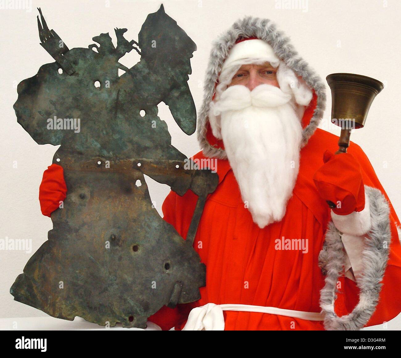 (dpa) - The Mayor, Roland Halang, dressed up as Santa Claus holds up a century-old weather vane in the shape of 'servant Rupprecht' (Knecht Rupprecht) in Ilberstedt, Germany, 8 December 2003. According to research, the figure of Knecht Rupprecht originates from Ilberstedt. 1000 years ago in this town, a priest of the name Rupprecht or Rupert is said to have cursed a group of 18 pag Stock Photo