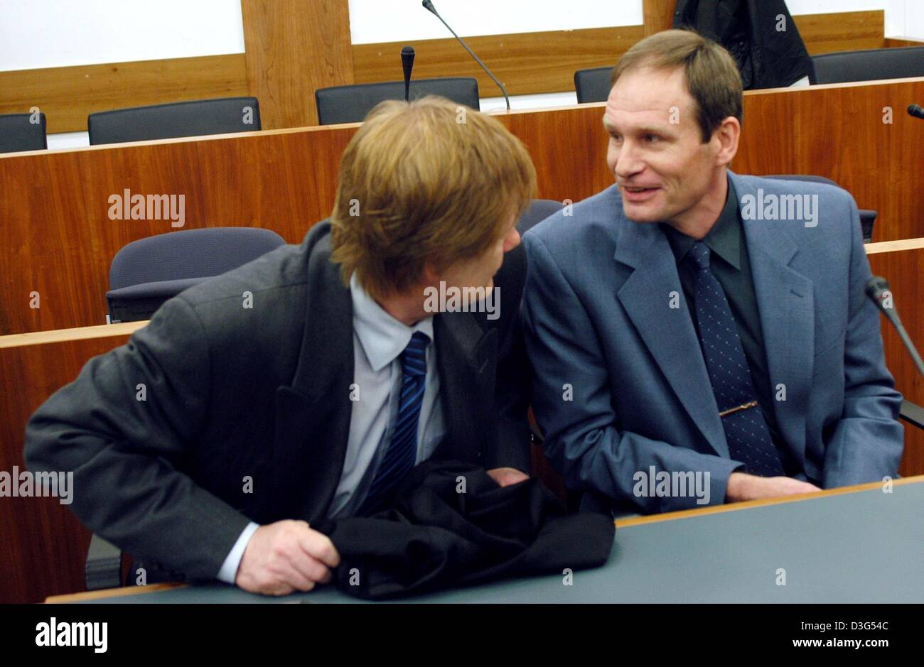 (dpa) - 42-year-old German computer specialist Armin Meiwes (R) chats with his lawyer Harald Ermel during the second day of his trial at the district court in Kassel, Germany, 8 December 2003. The court was set to view video tapes showing how the self-declared cannibal killed, cut up and ate his victim. The second day of the murder trial of Meiwes began with evidence to be given by Stock Photo