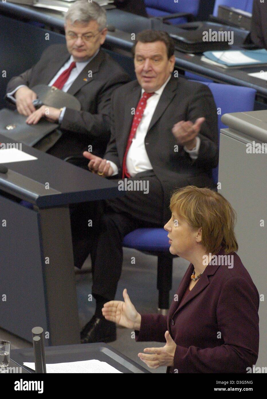 (dpa) - German Chancellor Gerhard Schroeder (C) and Foreign Minister and Vice Chancellor Joschka Fischer (L) listen to a speech by opposition leader Angela Merkel during a budget debate in the Bundestag in Berlin, 26 November 2003. Opposition parties accused Schroeder's government of bringing Germany to the 'brink of bankruptcy' by continuing heavy borrowing despite a flat economy. Stock Photo