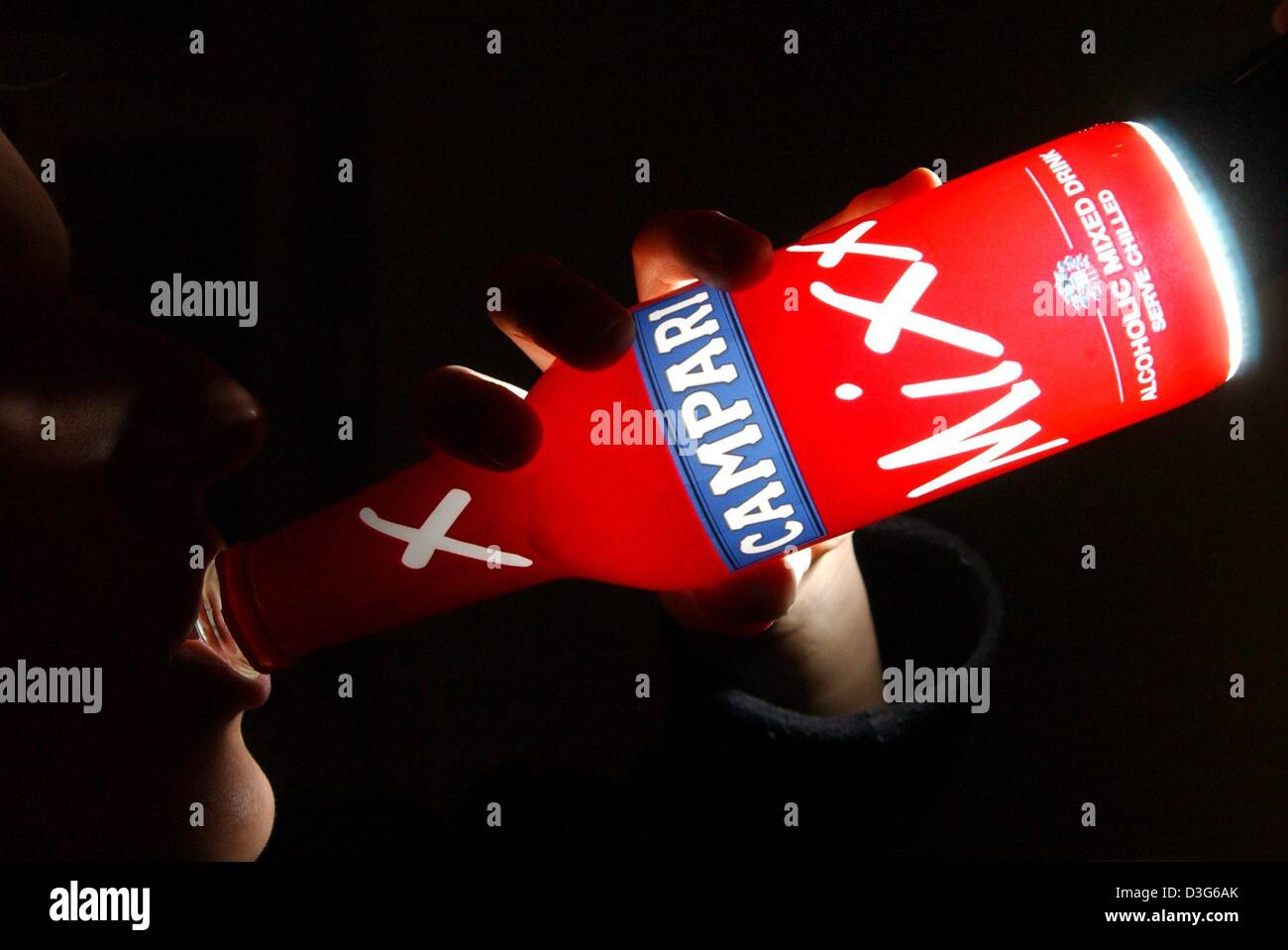 (dpa) - A young woman drinks from an illuminated red bottle of alcopops by 'Campari' in Frankfurt Main, Germany, 24 October 2003. The bottles are predominantly coloured in bright green, dark red, bright yellow or white colours which glow in the faint disco light. The name on the labels remind of foreign countries and adventures and their contents tastes sweet and tangy. 'Alcopops'  Stock Photo