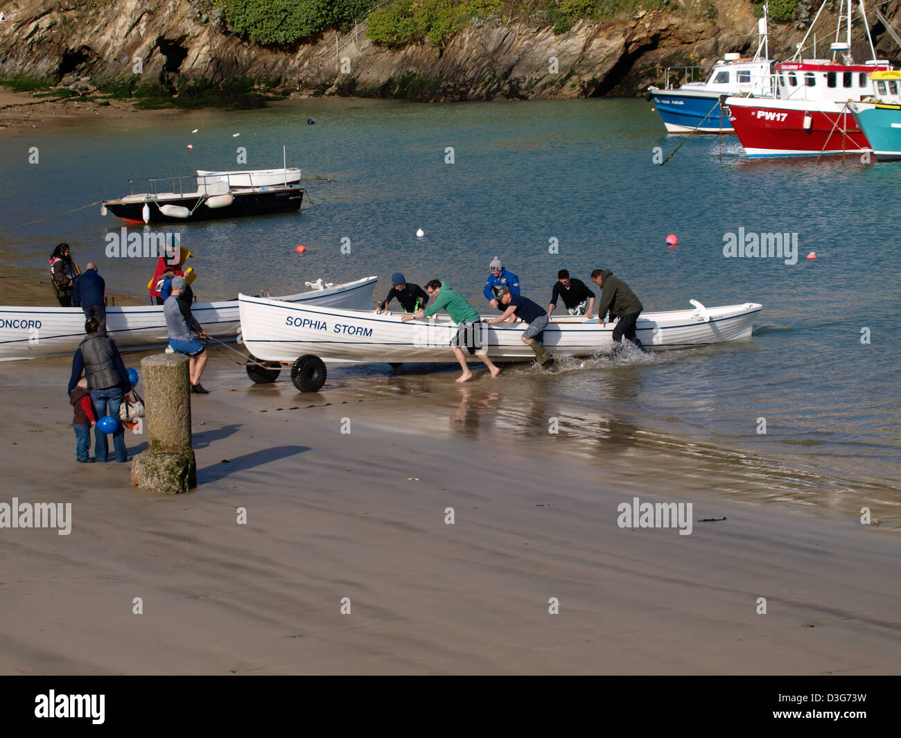 Pulling a gig surfboat out of the water, Newquay, Cornwall, UK Stock Photo