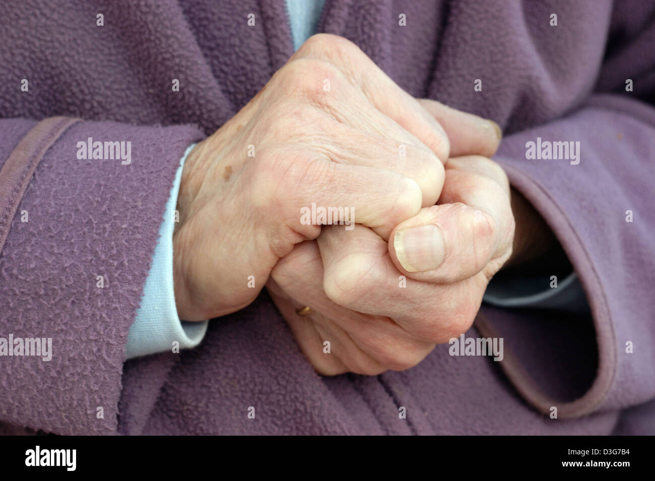 Close up of hands of an elderly woman wearing a fleece jacket & a warm scarf trying to keep warm in cold conditions Stock Photo