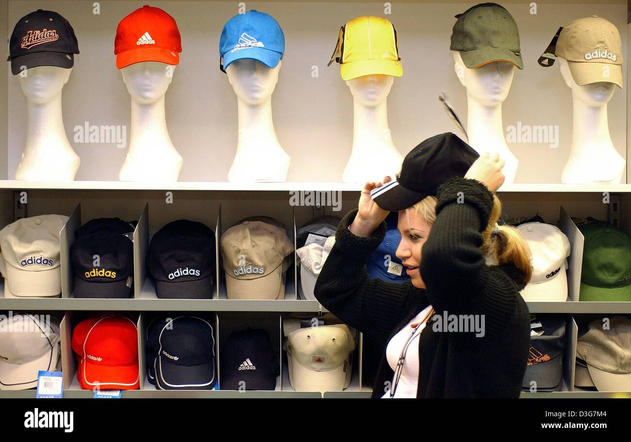 dpa) - A young woman tries on a billed cap at the adidas outlet-shop in  Herzogenaurach, Germany, 5 November 2003. adidas-Salomon, Europe's largest  manufacturer of sports wear and gear continues to hold