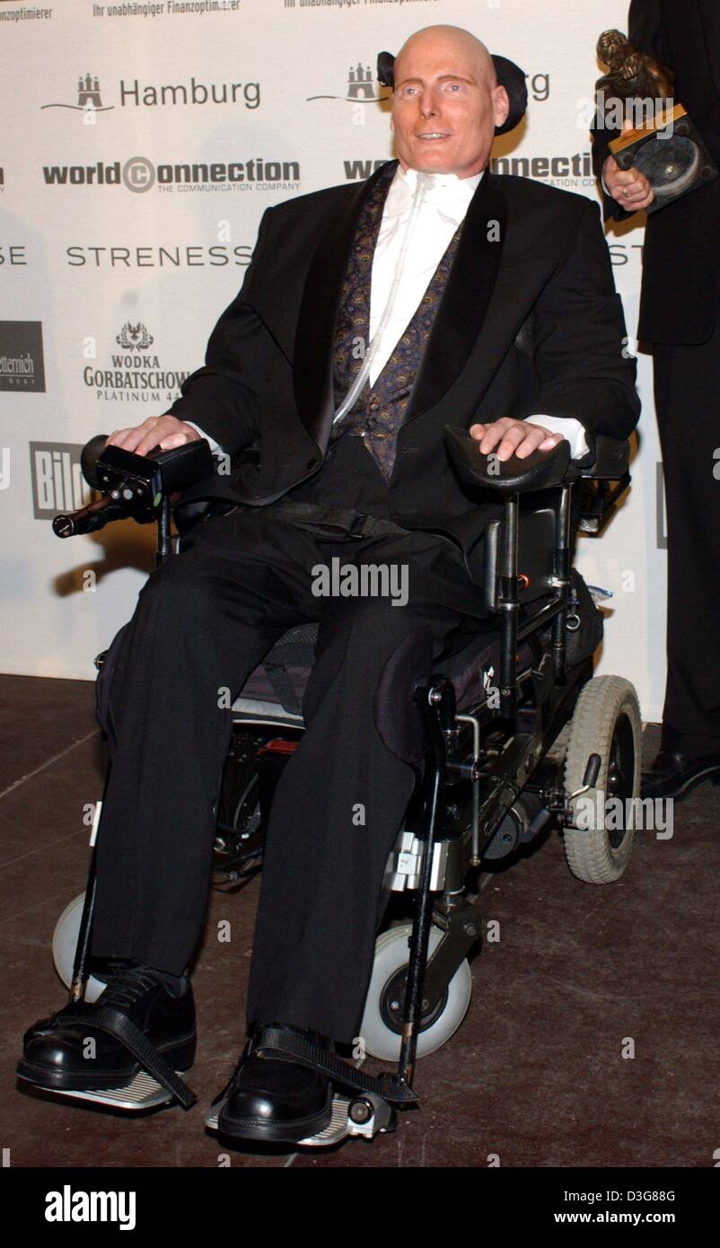 (dpa) - US actor Christopher Reeve, who has been paralysed since an accident, is pictured during the World Awards while one of his assistants is holding the trophy (background), in Hamburg, 22 October 2003. Reeve, who became famous as 'Superman', received the award in the category Lifetime Achievement for 'his commitment to disabled persons for whom he has become a beacon of hope.' Stock Photo