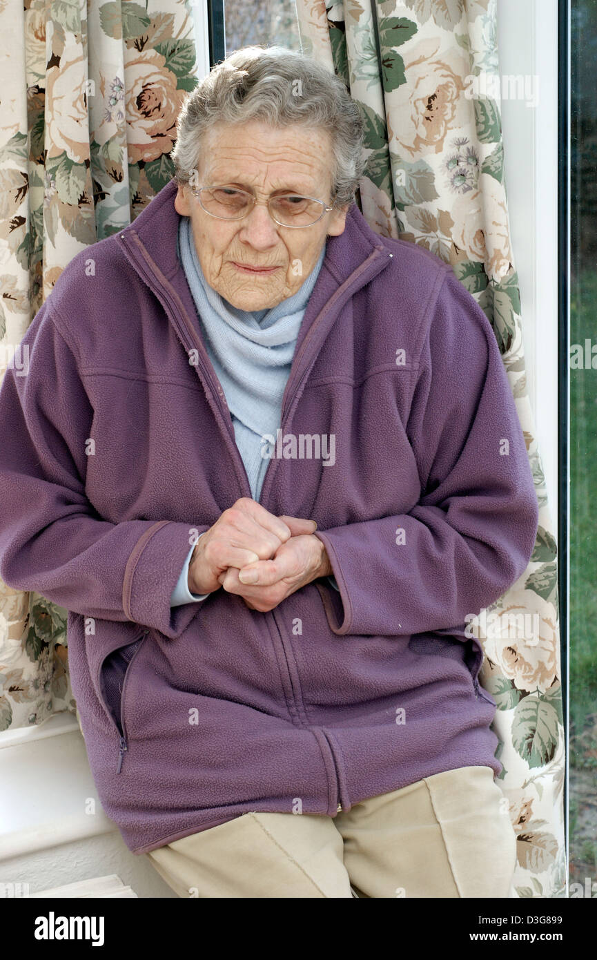 Elderly woman wearing a fleece jacket & a warm scarf trying to keep warm in cold conditions Stock Photo