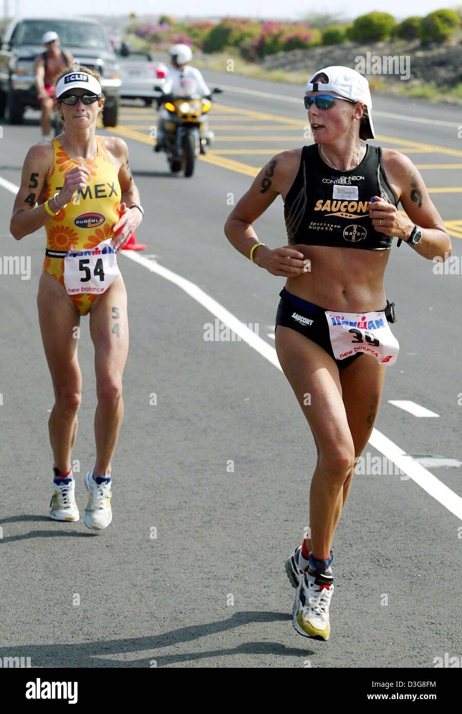 (dpa) - Canadian Lori Bowden (L) is on her way to win the 27th Iron Man competition in Kailua-Kona, Hawaii, 18 October 2003. In the background Germany's Nina Kraft (R), who took third place. Bowden won the women's event clocking 9:11:55 hours. The event included 3.8 km swimming, 180 km cycling and a marathon course. Stock Photo