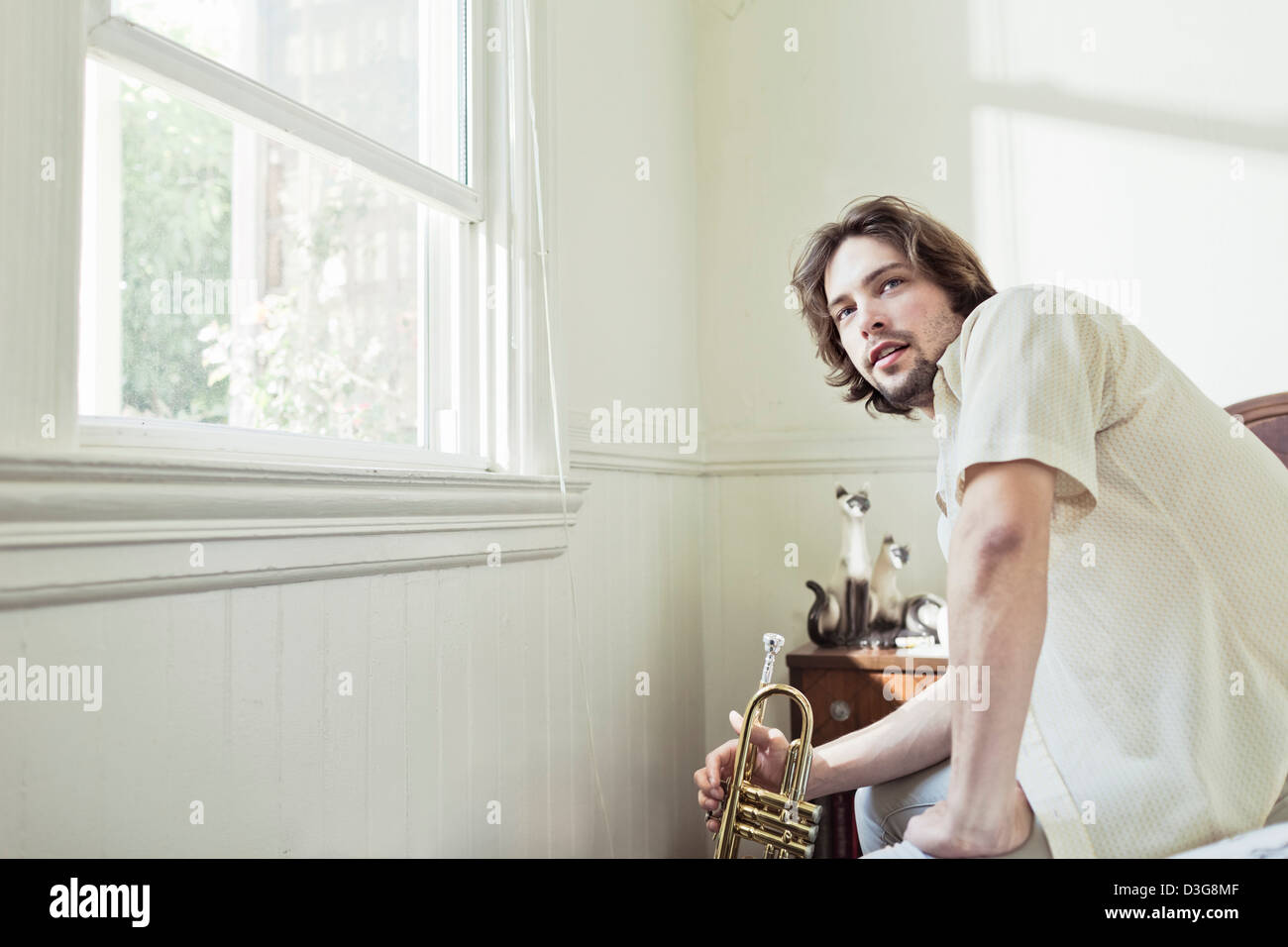 Young male trumpet player practicing at home in bed. Stock Photo