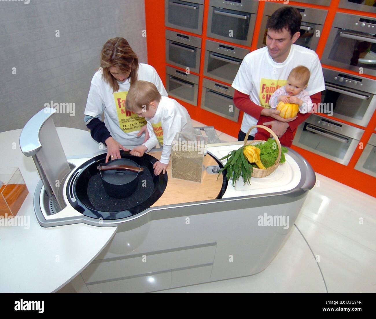 (dpa) - A family poses next to a design study of a kitchen by kitchen producer Bauknecht for photographers prior to the opening of the consumer fair 'family and home' at the fair premises in Stuttgart, Germany, 11 November 2004. The design study consists of a complete built-in kitchen with stove, sink, fume hood and compartments. The latest kitchen designs can be seen in Stuttgart  Stock Photo