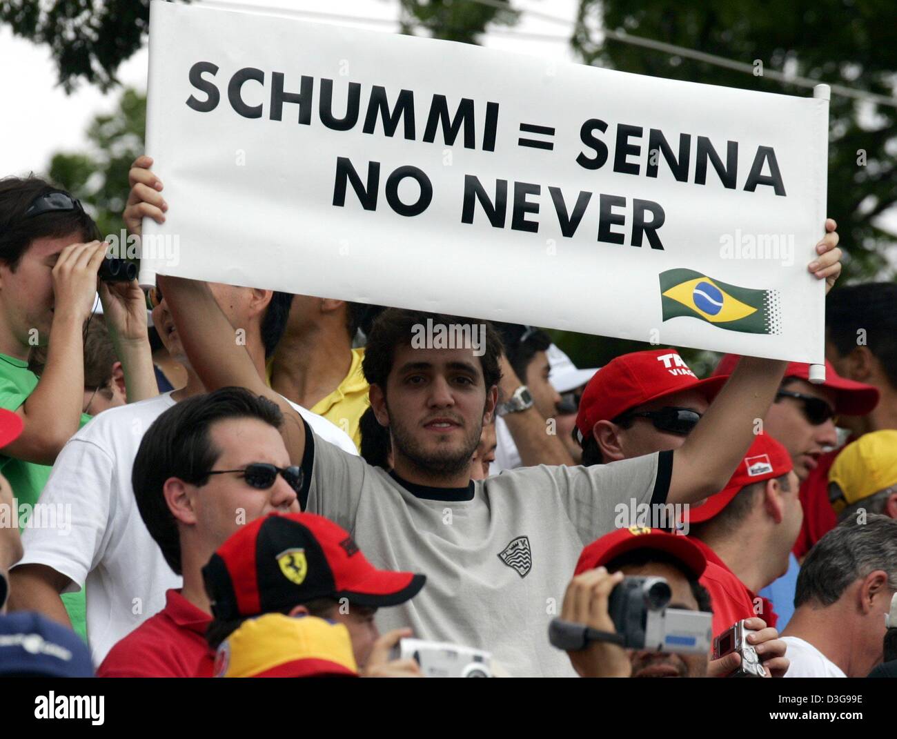 (dpa) - A Brazilian Formula One fan holds a banner with the inscription 'Schummi = Senna no never' in his hands during the Brazilian Formula One Grand Prix at the Interlagos circuit in Sao Paulo, Brazil, 24 October 2004. Brazilian Formula One world champion Ayrton Senna who died in an accident and German Formula One world champion Michael Schumacher (Ferrari) are often compared wit Stock Photo